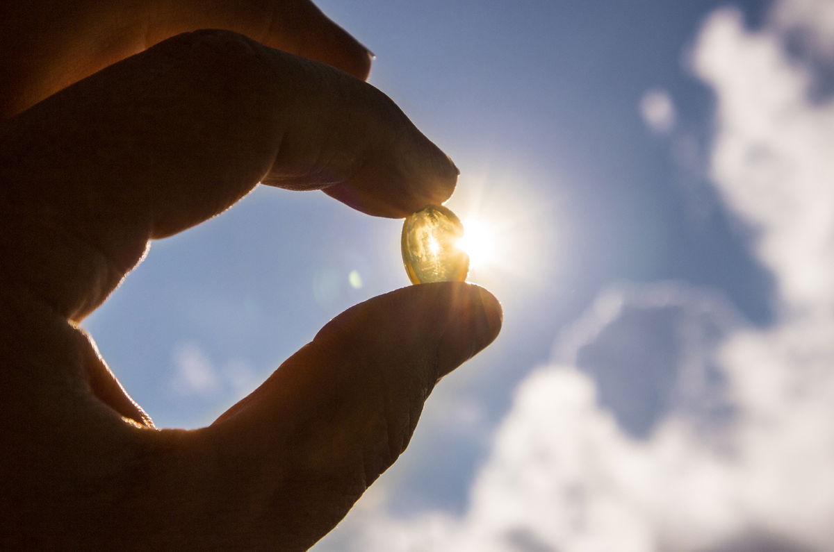 Vitamin D Kapsel wird in die Sonne gehalten – Vitamin-D-Versorgung und Sonnenlicht