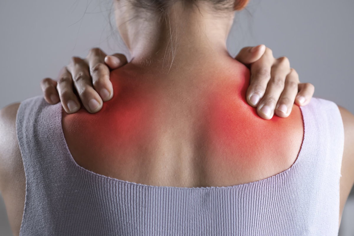 Rückenschmerzen bei Fibromyalgie – Frau hält sich den Rücken vor Schmerzen