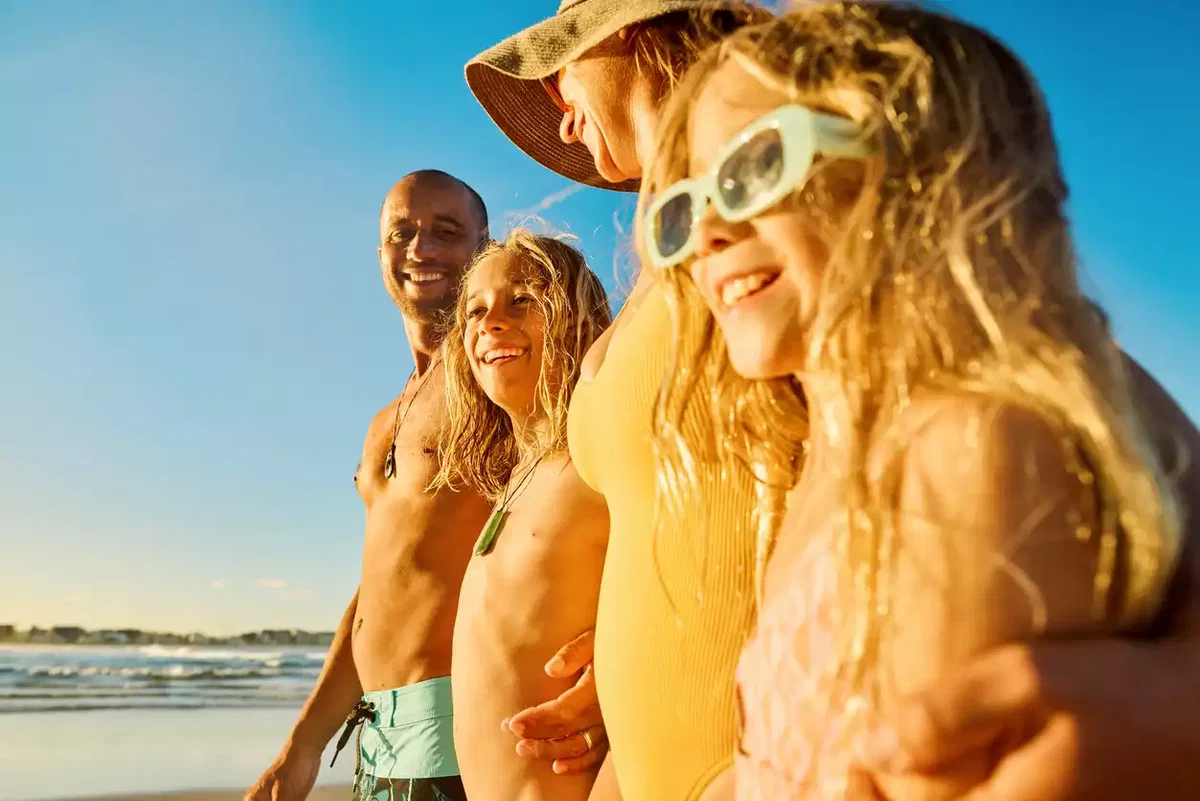 Glückliche Familie in der Sonne am Strand – Sonnenlicht und Vitamin D Spiegel im Urlaub